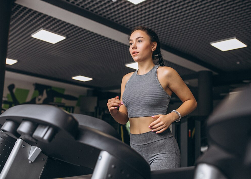 Девушка занимается кардио на беговой дорожке